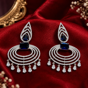 Silver-toned American Diamond statement earrings with royal sapphire blue crystals, tiered pavé-set concentric ovals, and dangling teardrop CZ stones by Glorious Jewels.