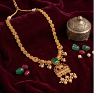 Antique gold Heritage temple necklace set featuring an emerald centerpiece with an intricate elephant motif pendant and matching flower-top jhumka earrings