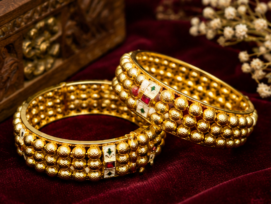 Pair of antique gold-plated broad bangles featuring three parallel rows of textured gold beads interspersed with white meenakari enamel blocks and ruby red stone accents from Glorious Jewels.