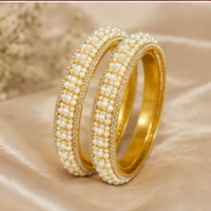 Pair of broad gold-plated bangles featuring a dense central band of woven ivory seed pearls bordered by sparkling pavé CZ crystal edges from Glorious Jewels.
