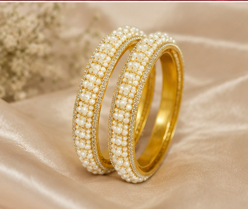 Pair of broad gold-plated bangles featuring a dense central band of woven ivory seed pearls bordered by sparkling pavé CZ crystal edges from Glorious Jewels.
