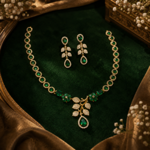 necklace featuring halo-set round emerald green stones leading to emerald-cut stones, green floral clusters, and a central pavé CZ leafy branch pendant with a teardrop emerald drop from Glorious Jewels.