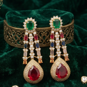 Gold-toned long chandelier drop earrings featuring an emerald-green halo top stud, multi-colored gemstone strands set with pavé cubic zirconia, and a large red ruby teardrop stone displayed on dark green velvet.