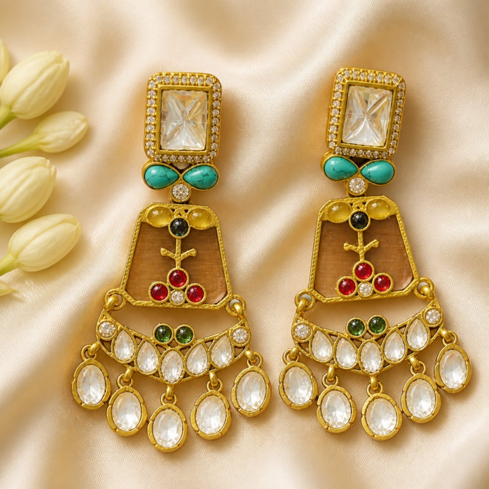 Close-up of gold uncut polki earrings on ivory silk with jasmine buds